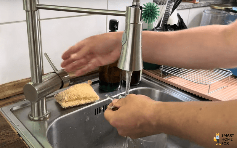 Das Mixmesser der Ninja Creami Eismaschine wird unter fließendem Wasser von Hand gespült.